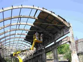 Operario en una plataforma elevadora desmontando la estructura de una cubierta