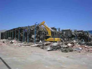 Excavadora entre los escombros de una nave industrial demolida