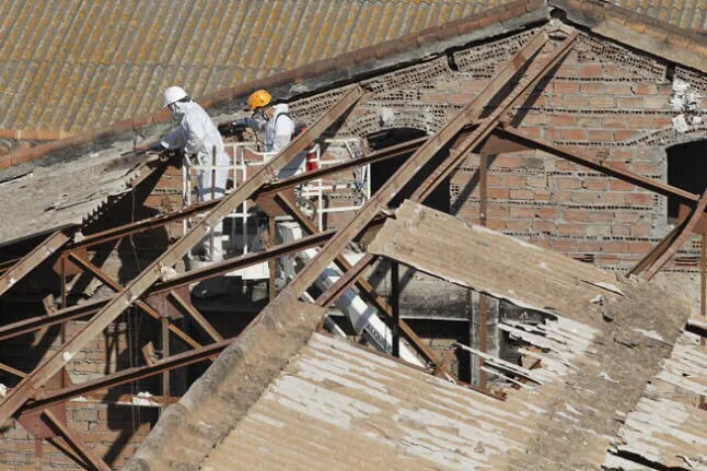 Operarios con trajes de protección retirando una cubierta de fibrocemento
